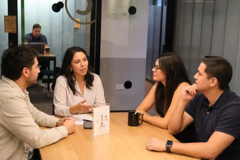 Four colleagues discussing work around an office table.