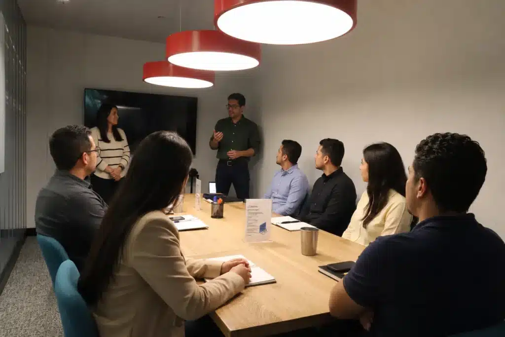 Colleagues gathered around a conference table beneath pendant lights.