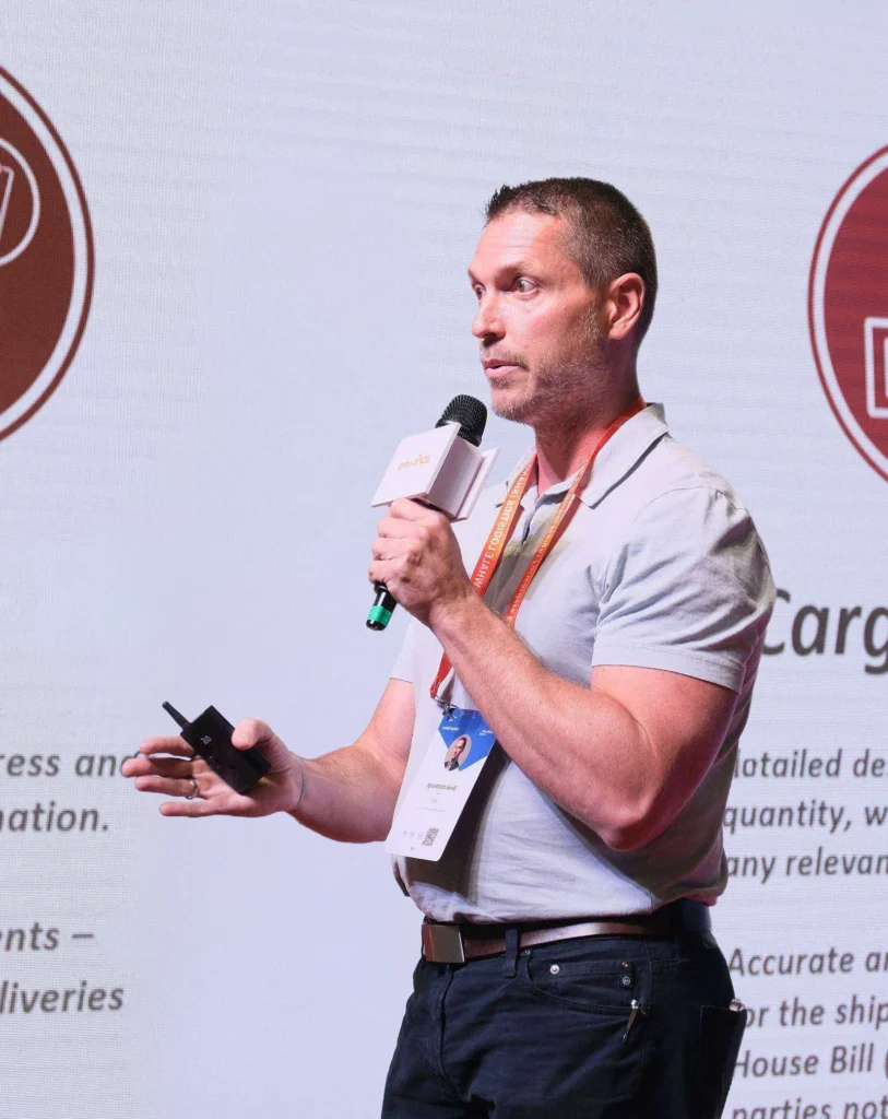 Derek Scarbrough, Co-Founder of TCA Staffing, speaking into a handheld microphone at an event.