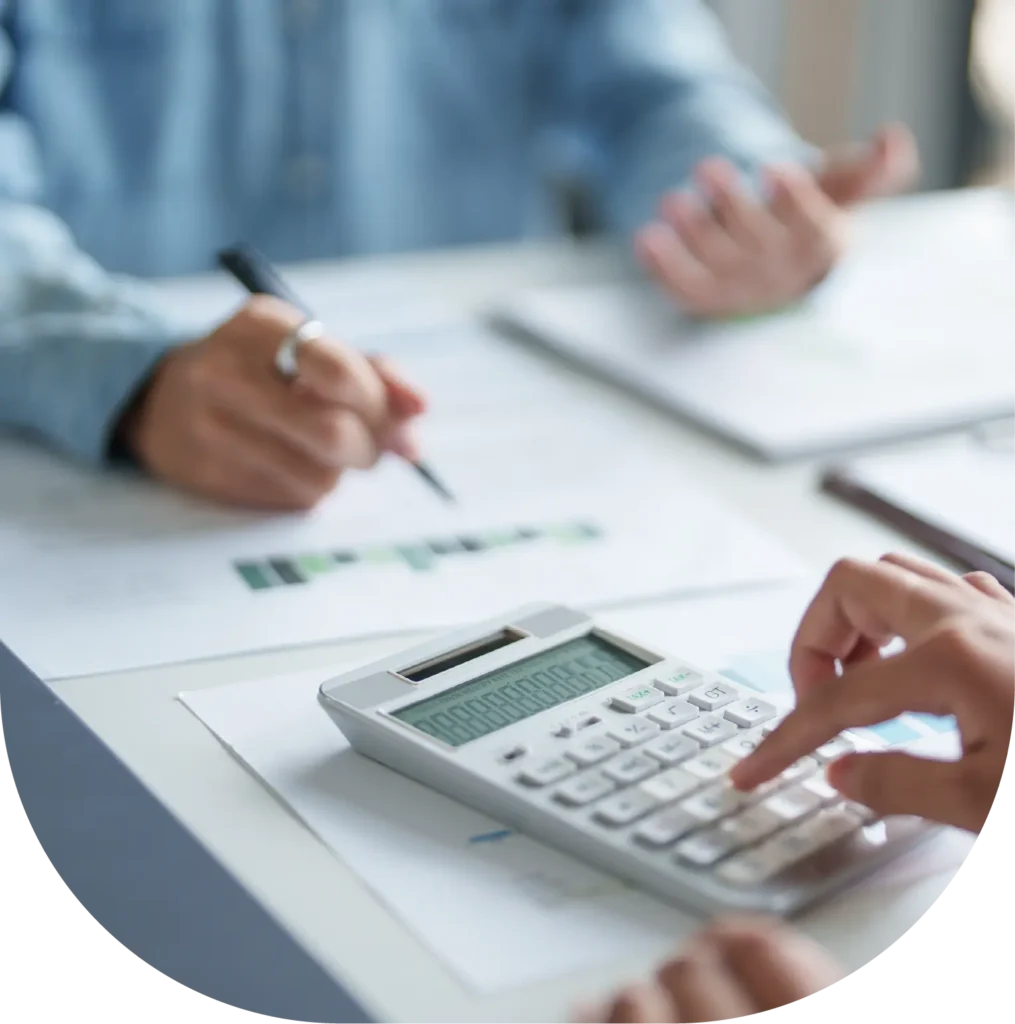 Hands using a calculator and writing on financial documents.